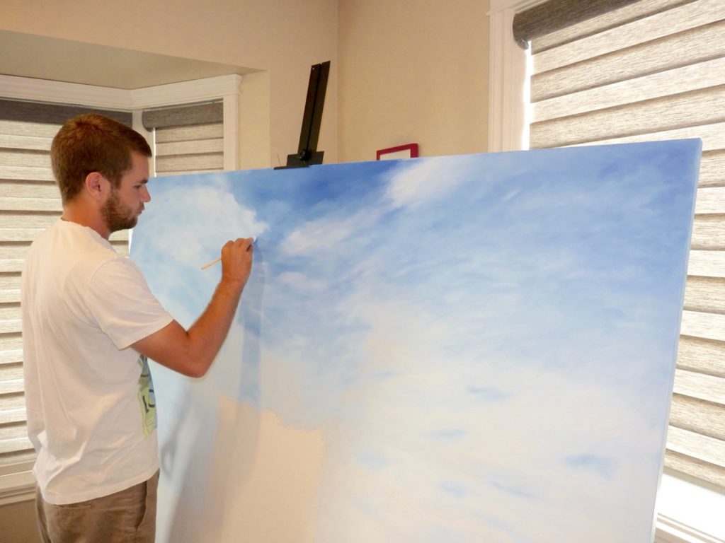 Canadian artist Brian Sloan painting the blue sky on a large stretched canvas